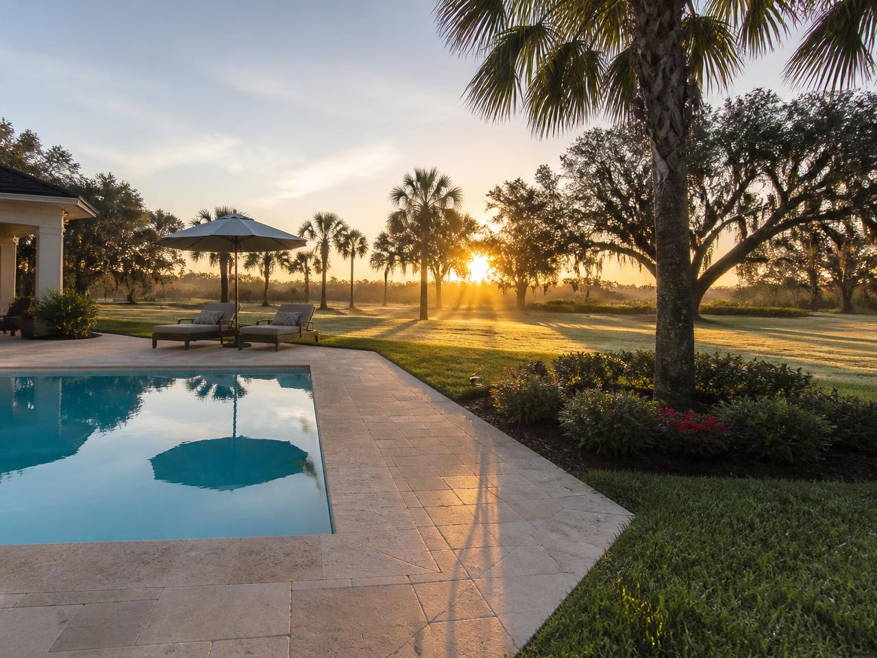 Travertine pool deck glowing in warm morning light with tropical landscaping