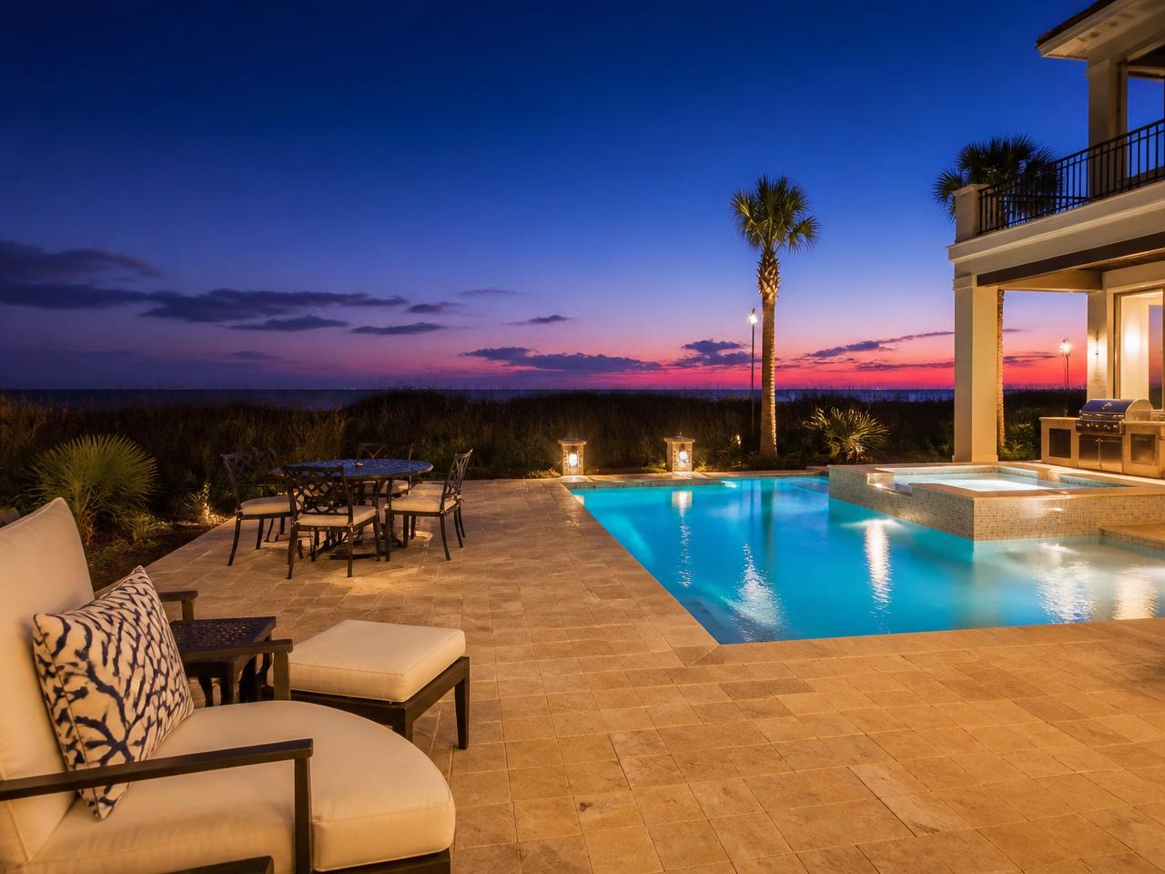 Natural stone pool deck with landscape lighting and resort-style seating at dusk